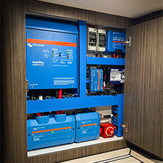 Organized van cabinet showing Victron inverters, chargers, and marine wiring layout