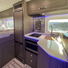 Induction cooktop and sink integrated into curved countertop with LED accent lighting