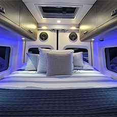 Soft pillows and linens under storage cabinets with downlights and speaker system