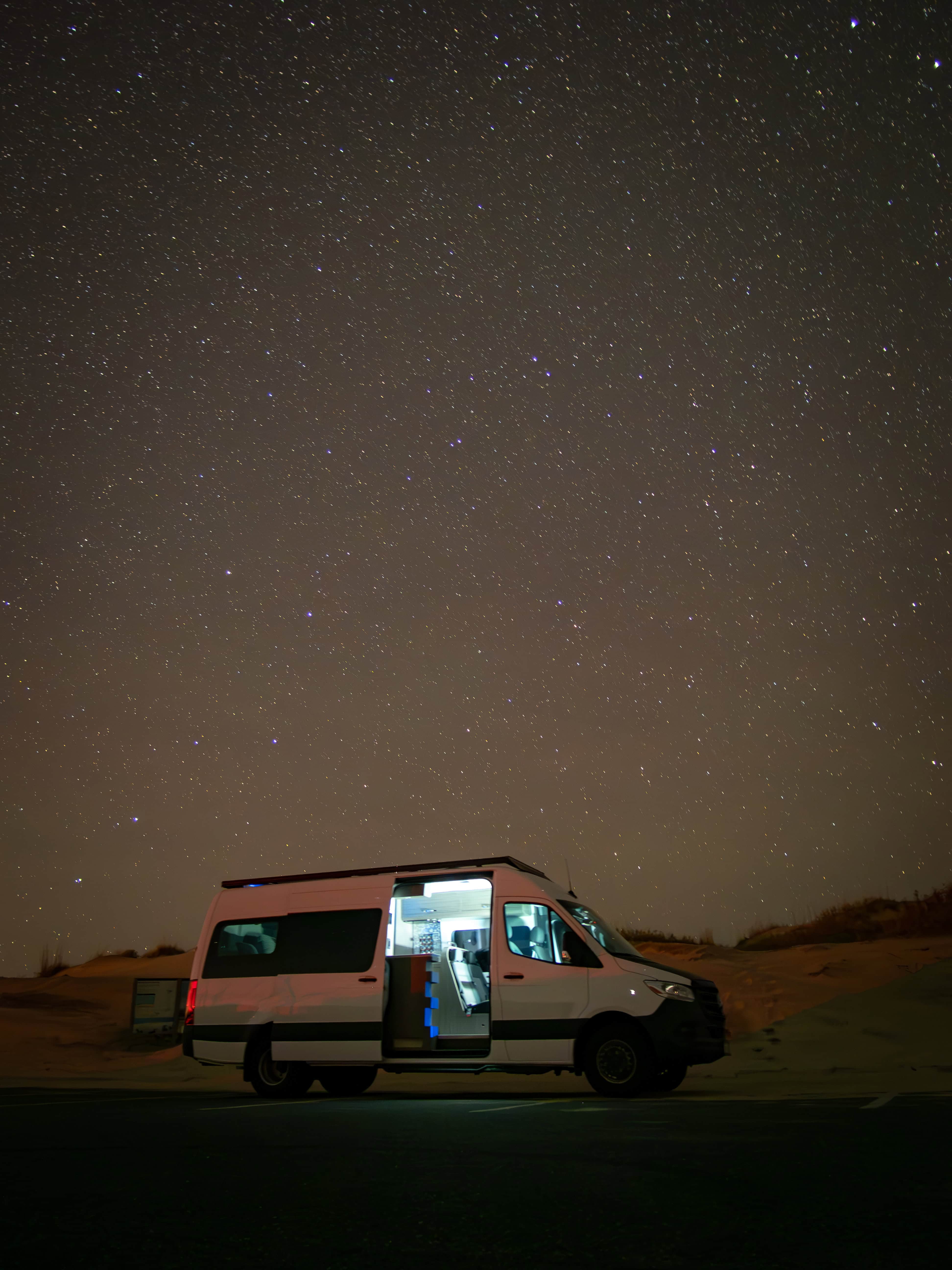 Icon Vans camper van with doors open under a starry desert night sky