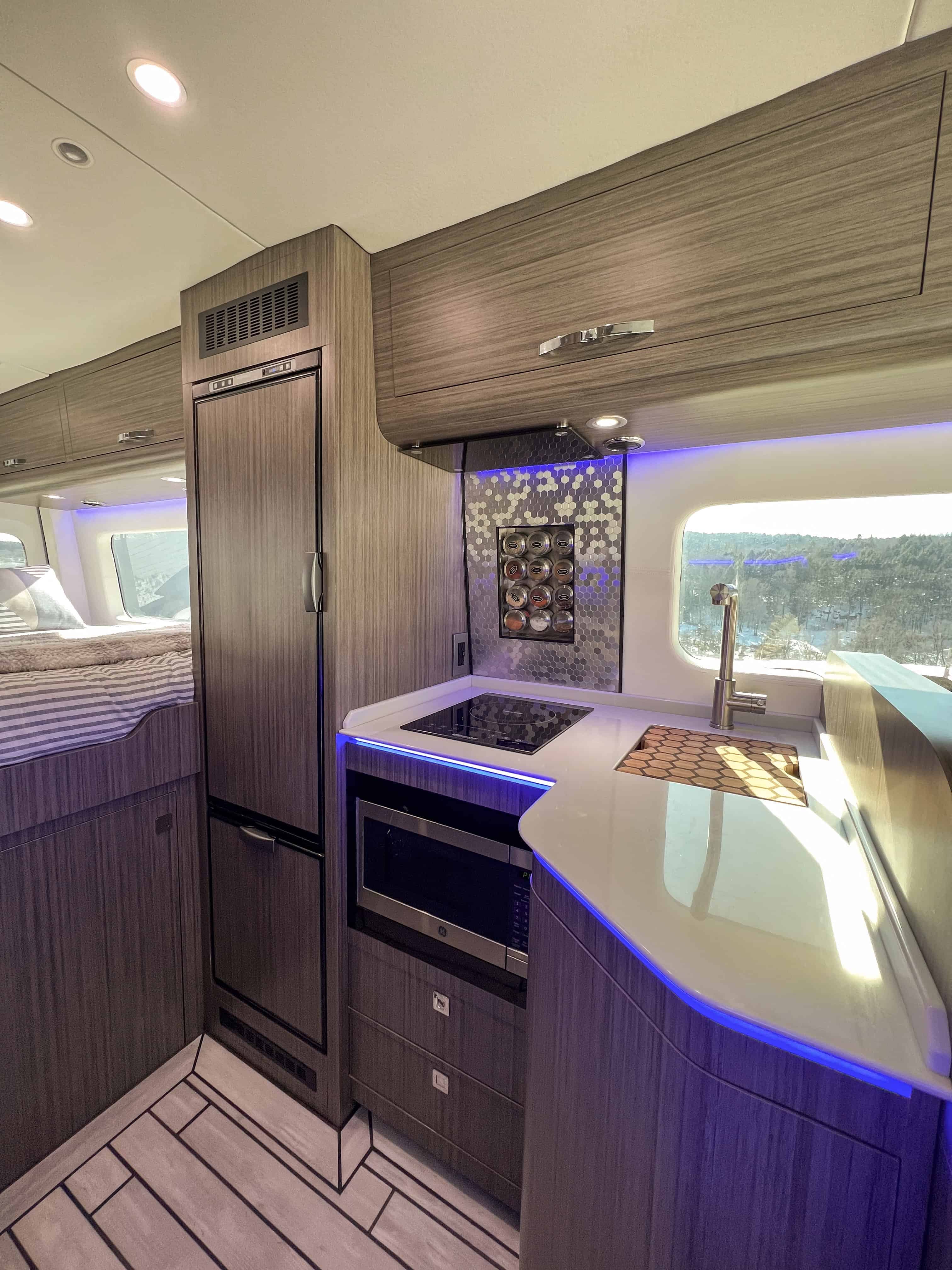 Van kitchen with induction cooktop, sink, LED lighting, and integrated cabinetry