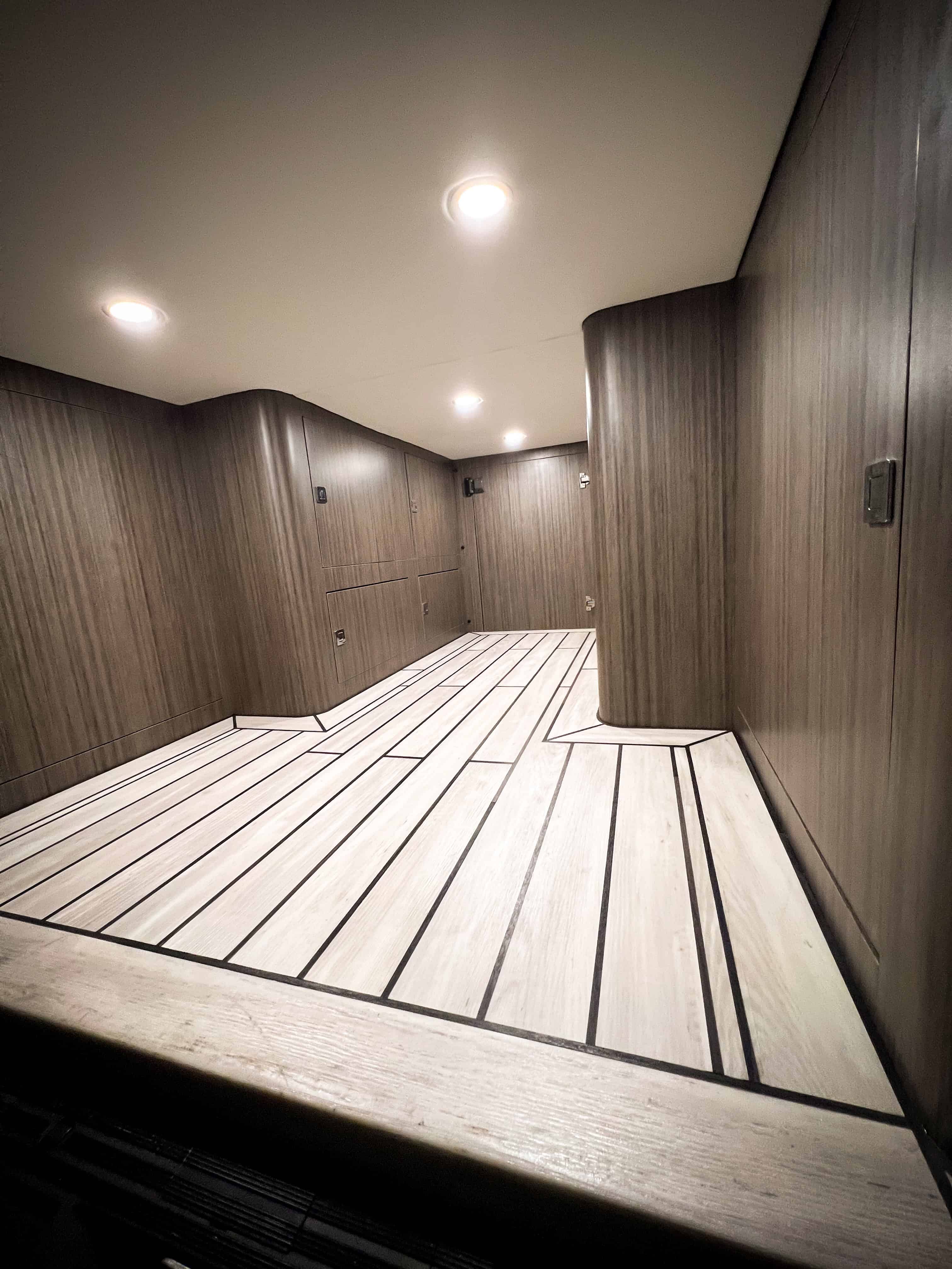 Interior cargo bay of camper van with wood-grain finish and marine-inspired flooring